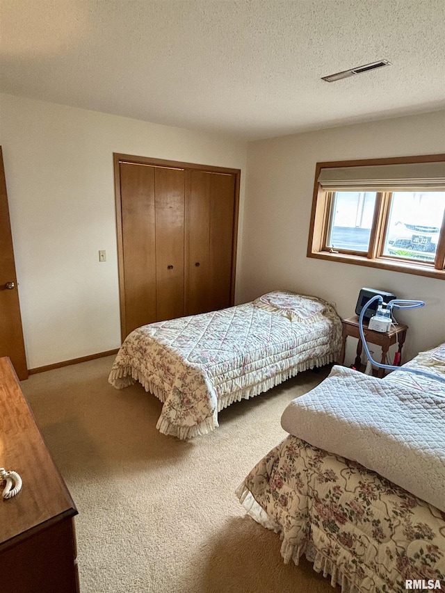 carpeted bedroom with a closet and a textured ceiling