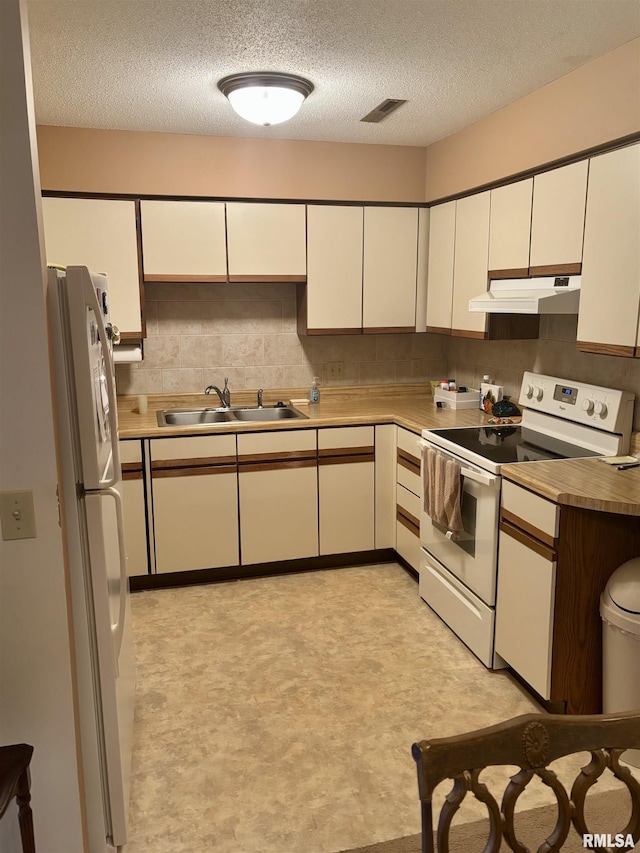 kitchen featuring white appliances, under cabinet range hood, a sink, light flooring, and a textured ceiling