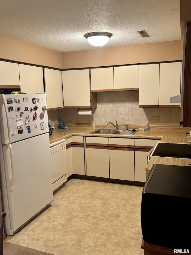 kitchen with white appliances, a sink, a textured ceiling, light countertops, and light flooring