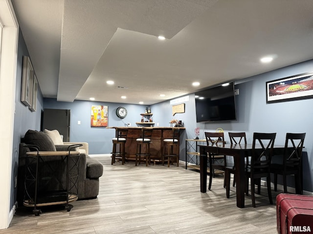 living room with a dry bar, light wood-type flooring, baseboards, and recessed lighting