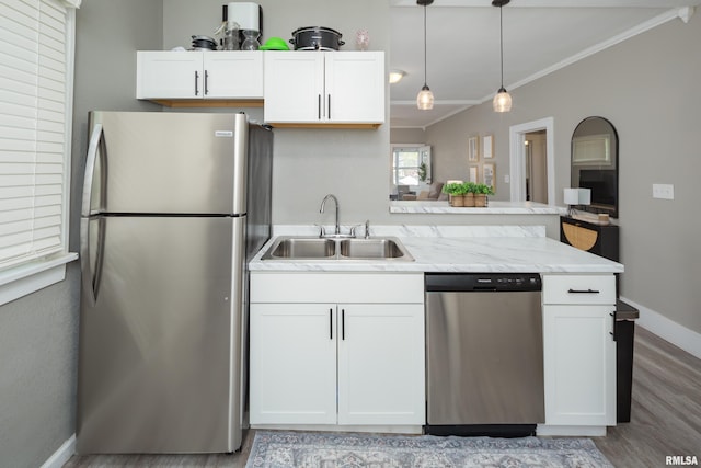 kitchen with stainless steel appliances, a sink, white cabinets, light wood finished floors, and ornamental molding