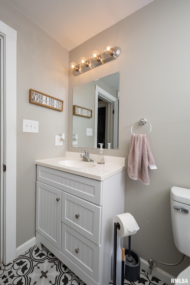 bathroom with baseboards, vanity, and toilet