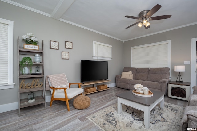 living area with wood finished floors, a ceiling fan, baseboards, and ornamental molding