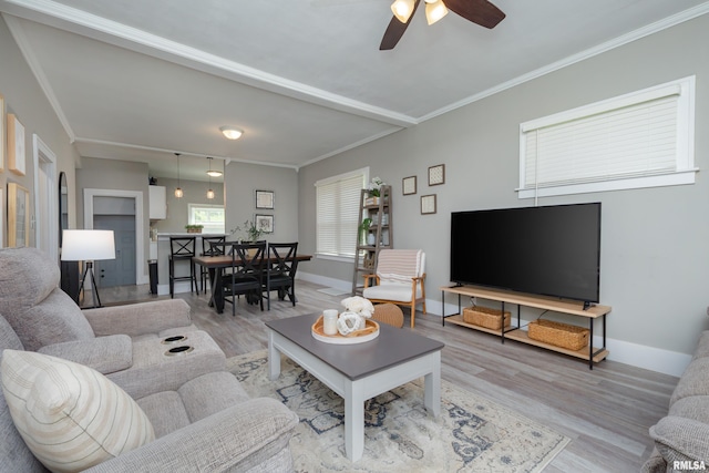 living area with wood finished floors, ceiling fan, ornamental molding, and baseboards