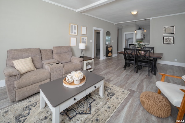 living room with light wood finished floors, ornamental molding, baseboards, and arched walkways