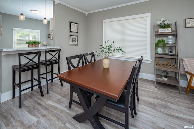 dining room with light wood-style floors, crown molding, and baseboards