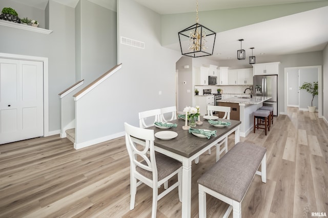 7 Welcome Center Ct, Le Claire, IA 52753 - dining room with light wood-type flooring, a chandelier, and stairs