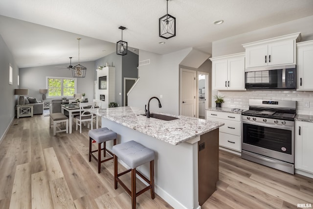7 Welcome Center Ct, Le Claire, IA 52753 - kitchen featuring stainless steel appliances, light wood finished floors, lofted ceiling, tasteful backsplash, and white cabinetry