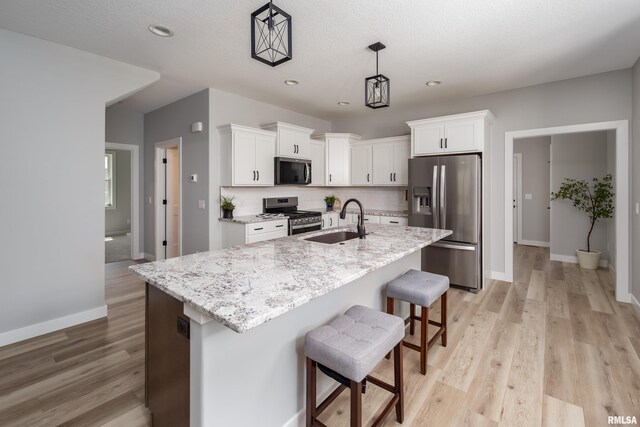 7 Welcome Center Ct, Le Claire, IA 52753 - kitchen with appliances with stainless steel finishes, white cabinetry, tasteful backsplash, light wood finished floors, and a breakfast bar area