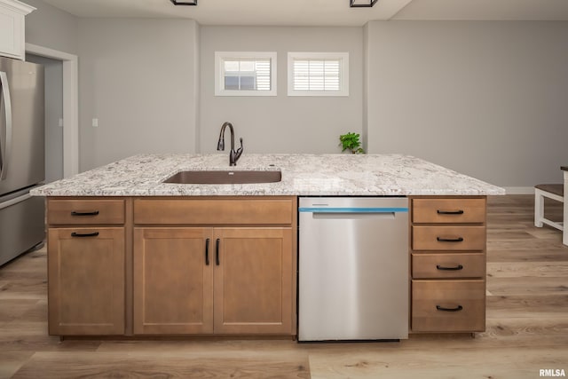 7 Welcome Center Ct, Le Claire, IA 52753 - kitchen with stainless steel appliances, light stone counters, light wood-type flooring, and a center island with sink