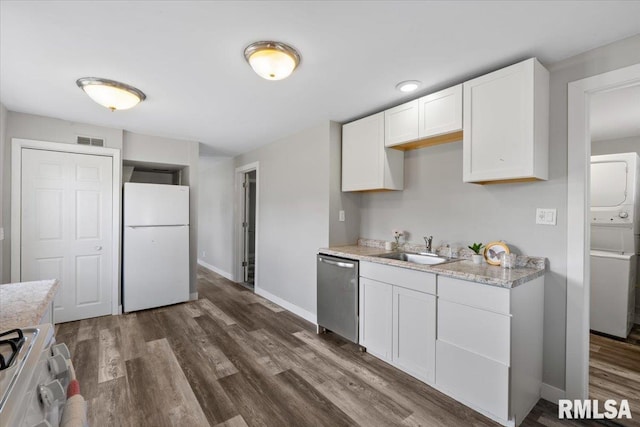 kitchen featuring freestanding refrigerator, stainless steel dishwasher, a sink, stove, and estacked washer and dryer