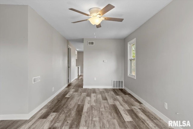 empty room featuring wood finished floors, a ceiling fan, and baseboards