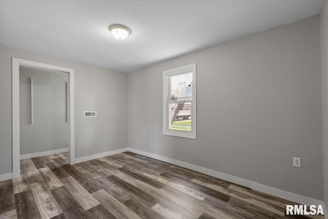 spare room featuring wood finished floors and baseboards