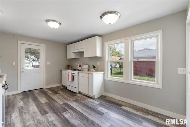 kitchen featuring white range with gas cooktop, plenty of natural light, light countertops, and white cabinetry