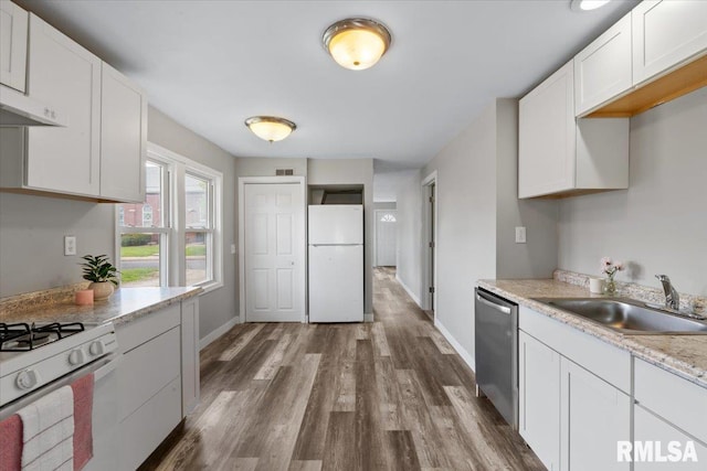 kitchen featuring white appliances, a sink, dark wood finished floors, light countertops, and baseboards