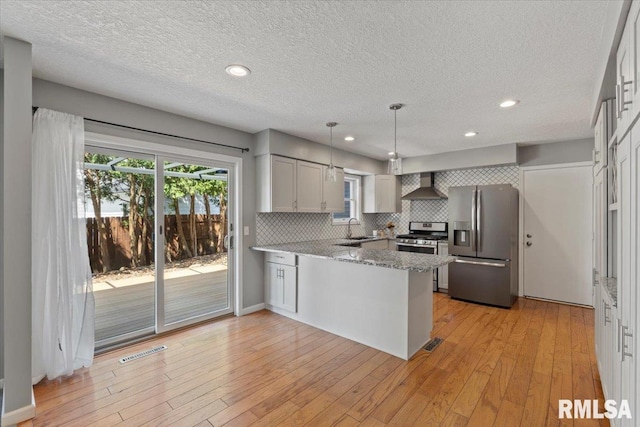 4690 Lindbergh Dr, Bettendorf, IA 52722 - kitchen with stainless steel appliances, wall chimney exhaust hood, a sink, a peninsula, and tasteful backsplash