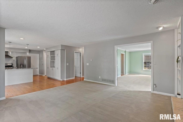 4690 Lindbergh Dr, Bettendorf, IA 52722 - unfurnished living room featuring light carpet, a textured ceiling, and baseboards