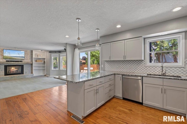 4690 Lindbergh Dr, Bettendorf, IA 52722 - kitchen featuring dishwasher, a sink, a peninsula, open floor plan, and a textured ceiling