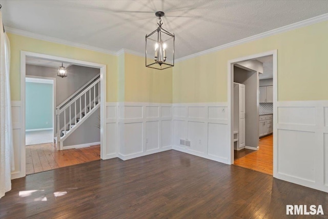 4690 Lindbergh Dr, Bettendorf, IA 52722 - unfurnished dining area featuring a chandelier, wood finished floors, a decorative wall, stairs, and wainscoting