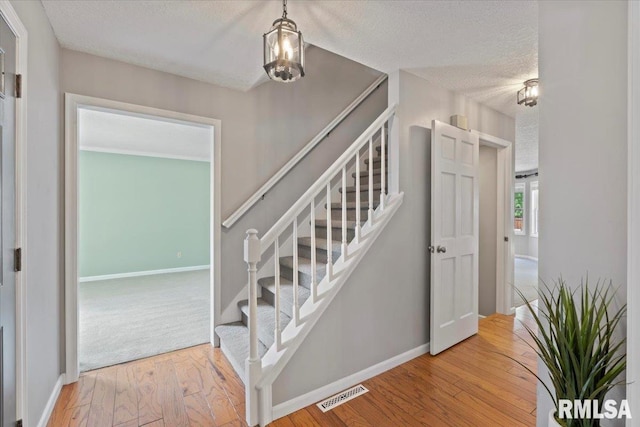 4690 Lindbergh Dr, Bettendorf, IA 52722 - stairway featuring a textured ceiling, wood finished floors, and baseboards