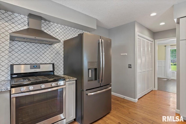 4690 Lindbergh Dr, Bettendorf, IA 52722 - kitchen with stainless steel appliances, wall chimney exhaust hood, baseboards, light wood-style floors, and light stone counters