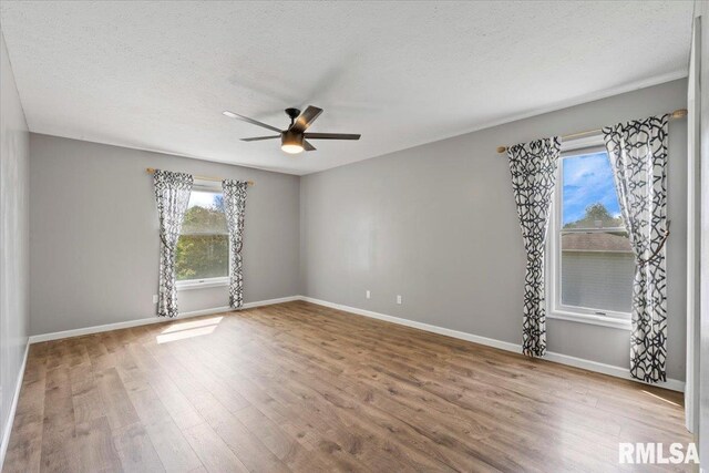 4690 Lindbergh Dr, Bettendorf, IA 52722 - empty room with wood finished floors, a ceiling fan, baseboards, and a textured ceiling
