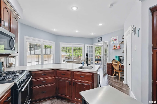 kitchen with a sink, reddish brown cabinets, light countertops, dark wood finished floors, and stainless steel microwave