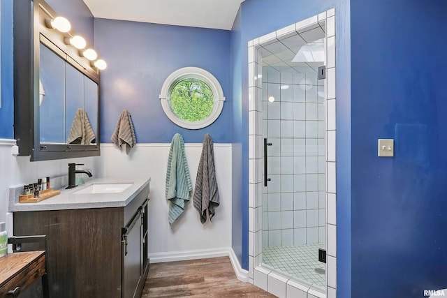 full bathroom with wood finished floors, a stall shower, vanity, and baseboards