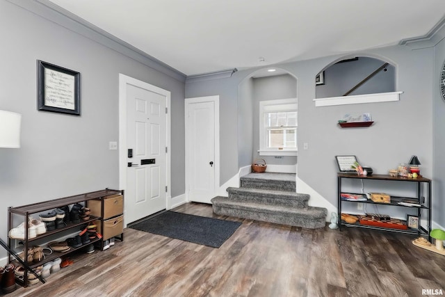 foyer entrance with wood finished floors, stairs, baseboards, ornamental molding, and recessed lighting