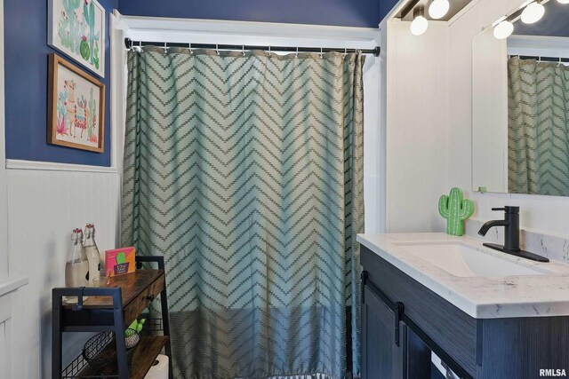 full bathroom featuring wainscoting, vanity, and curtained shower