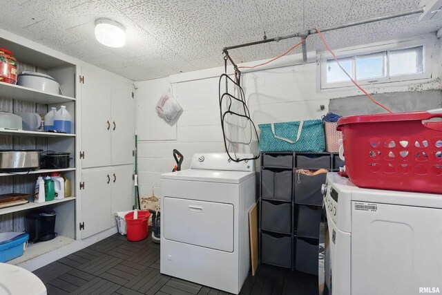 clothes washing area with washer and clothes dryer and concrete block wall