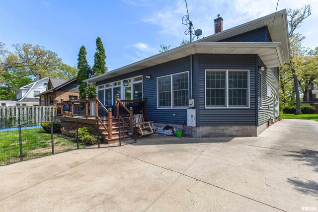 back of house with a deck, a chimney, and fence