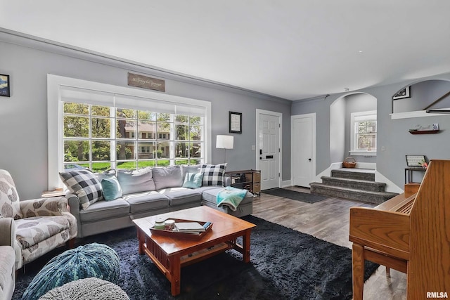 living area featuring wood finished floors, stairway, and arched walkways
