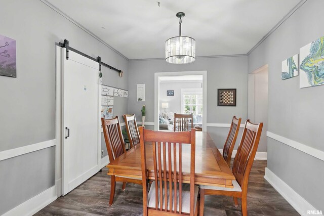 dining room with a barn door, wood finished floors, a chandelier, baseboards, and crown molding