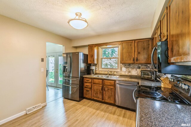 1960 Tam-O-Shanter Dr, Bettendorf, IA 52722 - kitchen with stainless steel appliances, a sink, dark countertops, brown cabinets, and a textured ceiling