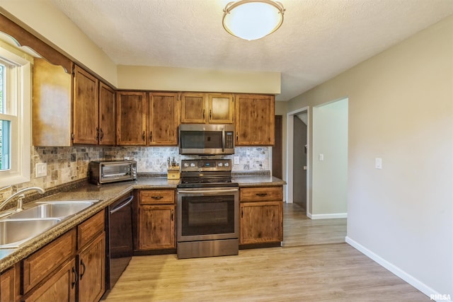 1960 Tam-O-Shanter Dr, Bettendorf, IA 52722 - kitchen with stainless steel appliances, a sink, decorative backsplash, brown cabinetry, and light wood-style flooring