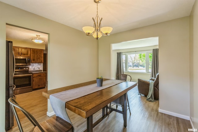 1960 Tam-O-Shanter Dr, Bettendorf, IA 52722 - dining area with a chandelier, light wood finished floors, and baseboards