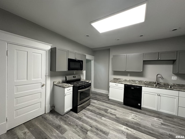 kitchen with black appliances, a sink, gray cabinets, wood finished floors, and baseboards