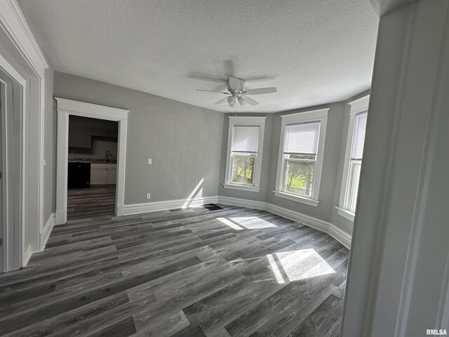 spare room featuring a textured ceiling, ceiling fan, dark wood-type flooring, baseboards, and a sink