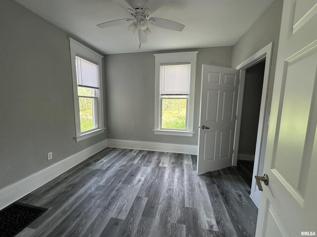 unfurnished bedroom with baseboards, multiple windows, dark wood-type flooring, and ceiling fan