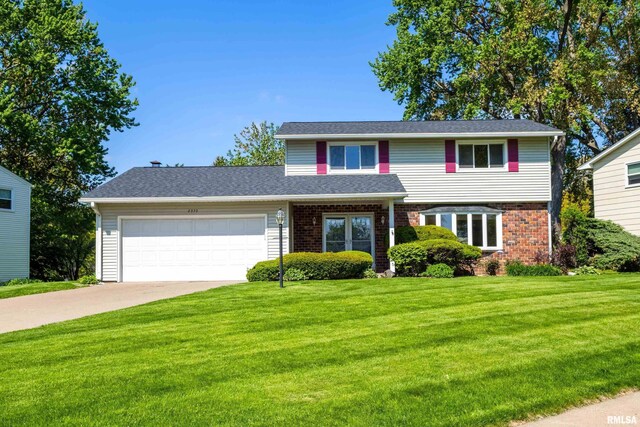 traditional-style house featuring a garage, a front yard, driveway, and brick siding
