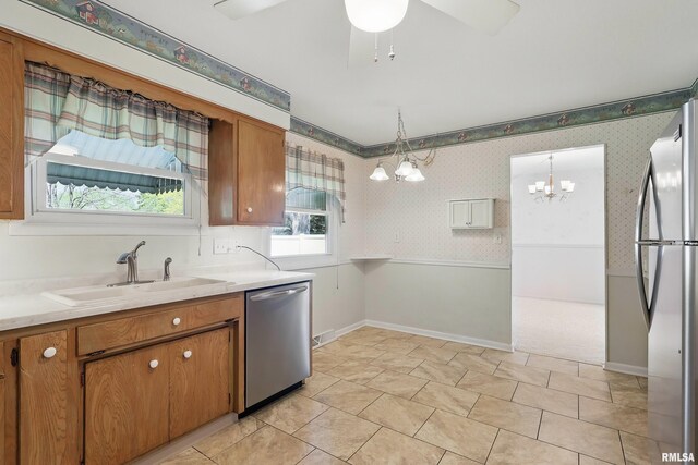 kitchen featuring stainless steel appliances, a sink, brown cabinetry, light countertops, and a ceiling fan