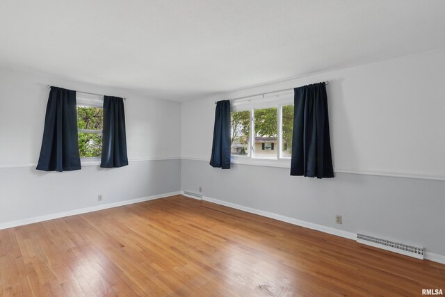 unfurnished room featuring light wood-type flooring, plenty of natural light, and baseboards