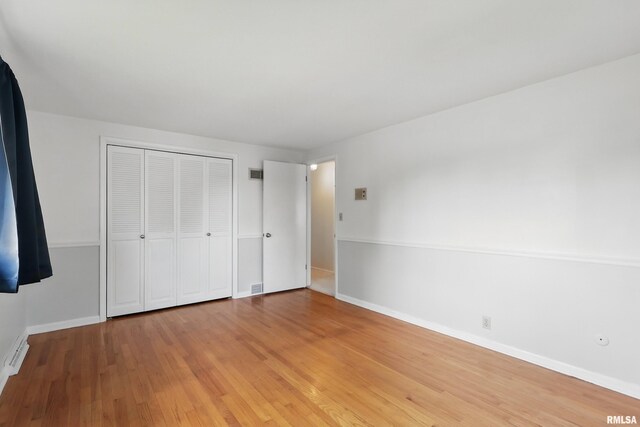 unfurnished bedroom with light wood-style flooring, a closet, and baseboards