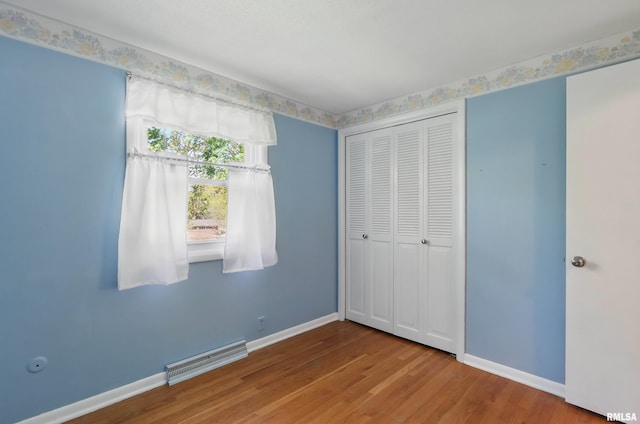 unfurnished bedroom with baseboards, wood finished floors, and a closet