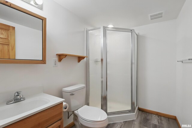 full bathroom with a stall shower, wood finished floors, vanity, and toilet