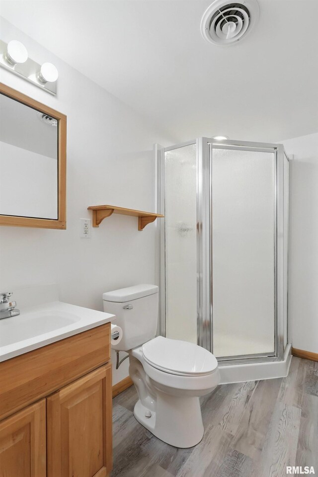 full bath with wood finished floors, a stall shower, vanity, toilet, and baseboards