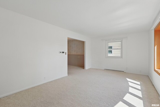 unfurnished room featuring carpet, baseboards, and a baseboard heating unit