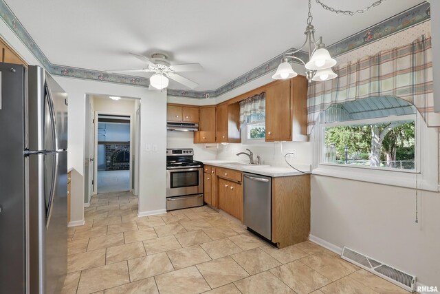 kitchen with stainless steel appliances, under cabinet range hood, a sink, light countertops, and ceiling fan
