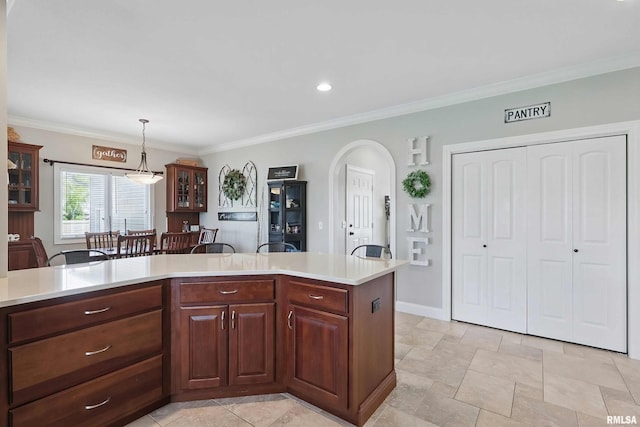 kitchen with light countertops, glass insert cabinets, arched walkways, decorative light fixtures, and ornamental molding